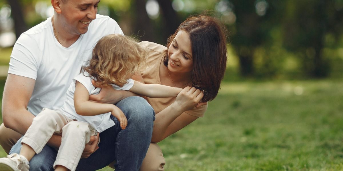 A joyous family playing together in a spacious green park, highlighting the family-friendly amenities available in Al Nahda.