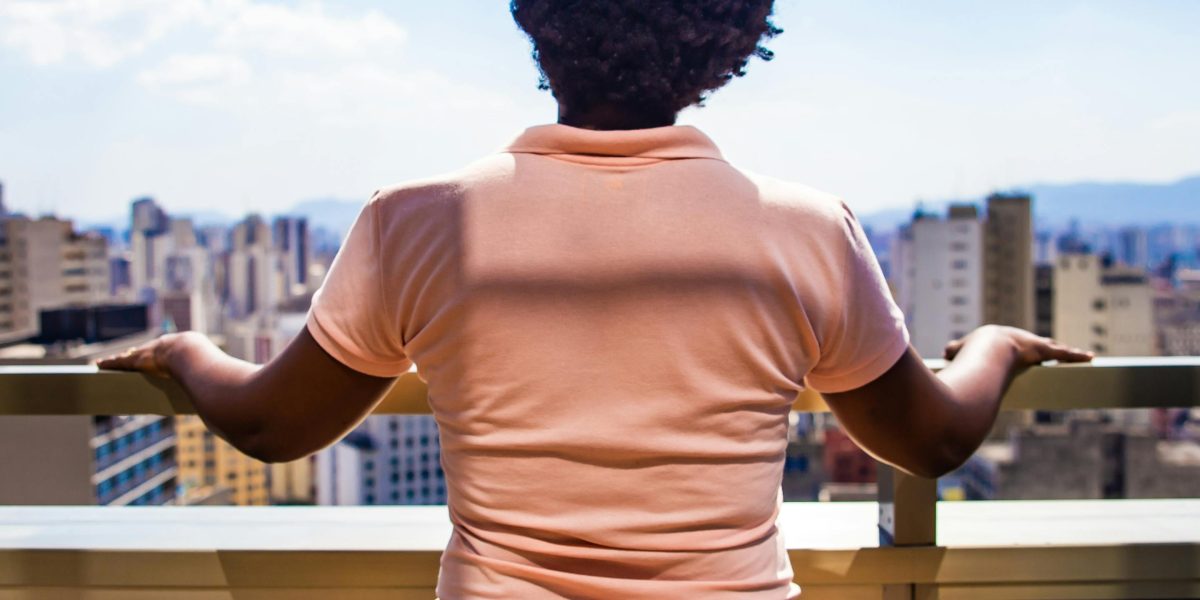 A person looks out over a bustling city, reflecting on real estate decisions.